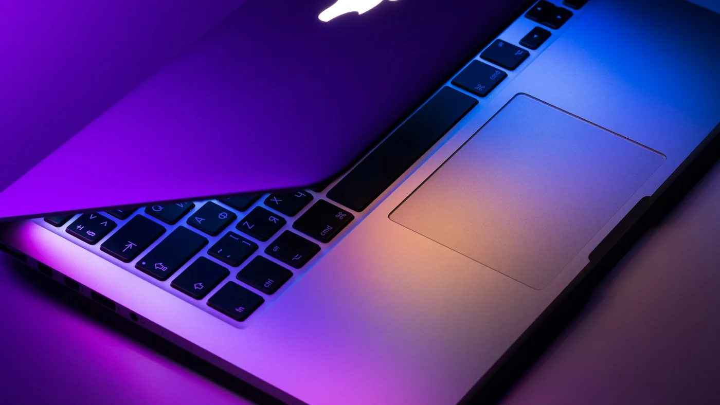 A MacBook on a warm wooden desk in a quiet studio workspace